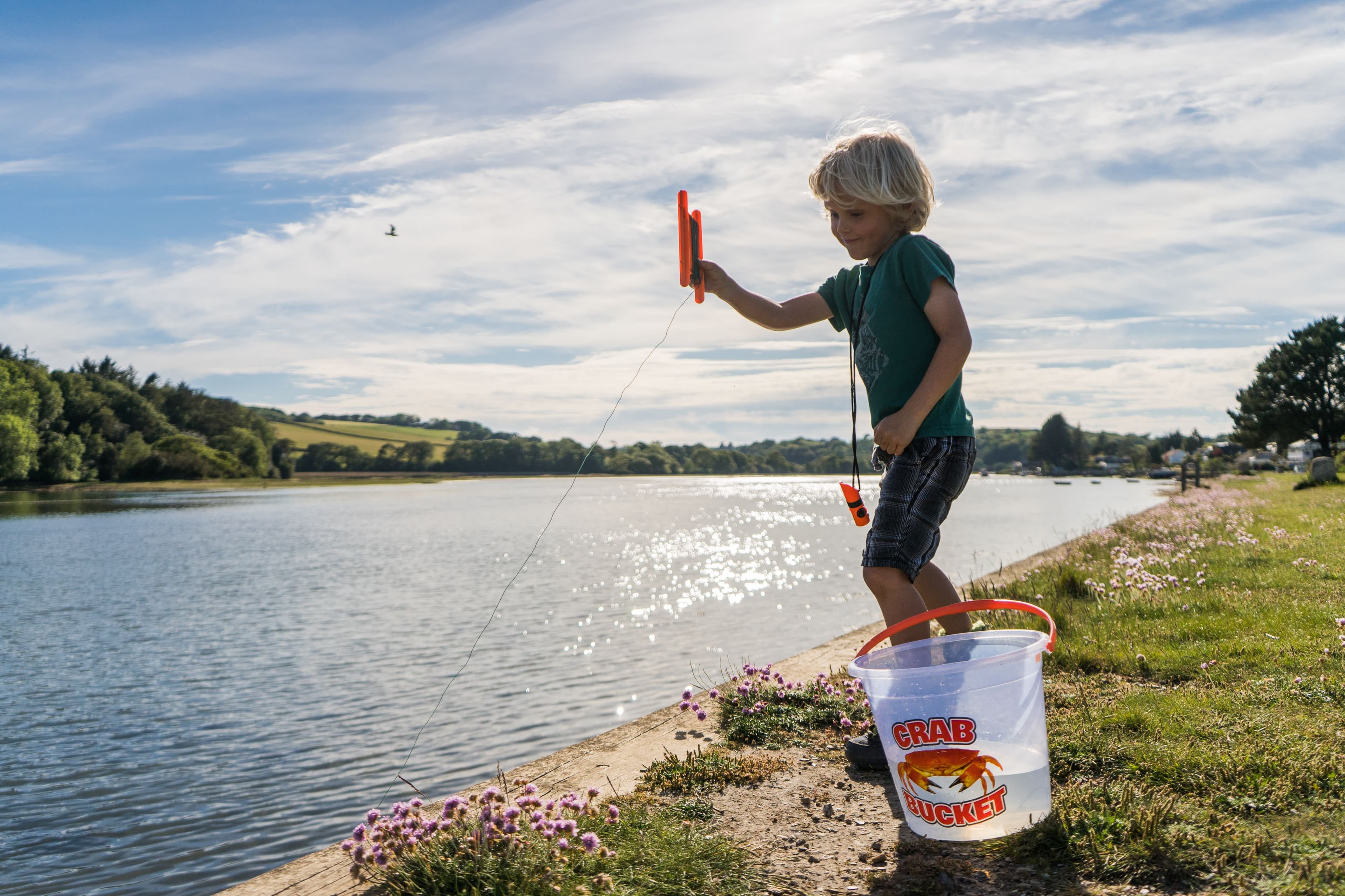 A small boy with a fishing net looking for crabs, in a small rock